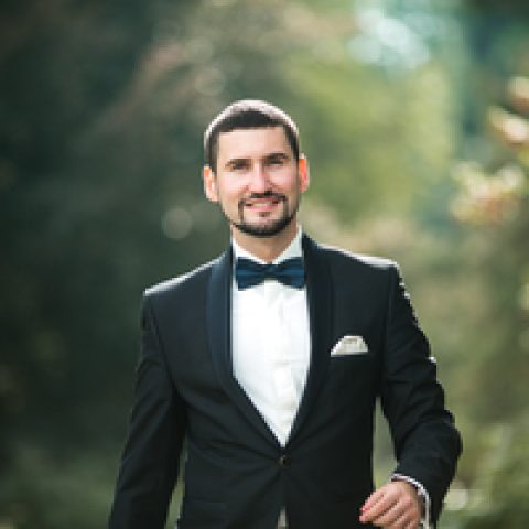 confident groom posing for the camera in the park